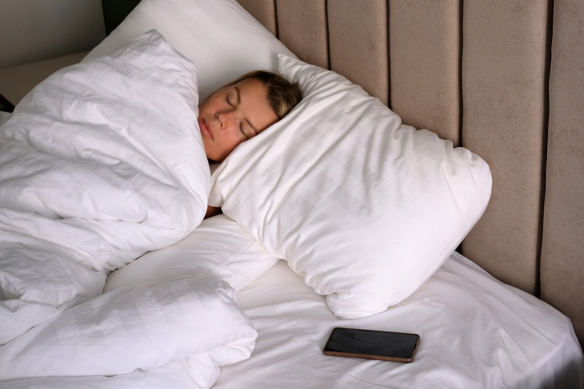sleeping woman in bed covered with white blanket